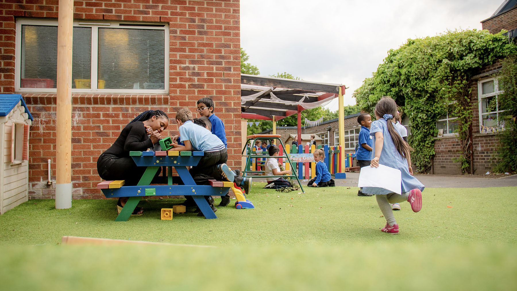Children playing in the reception outdoor area with a member of staff